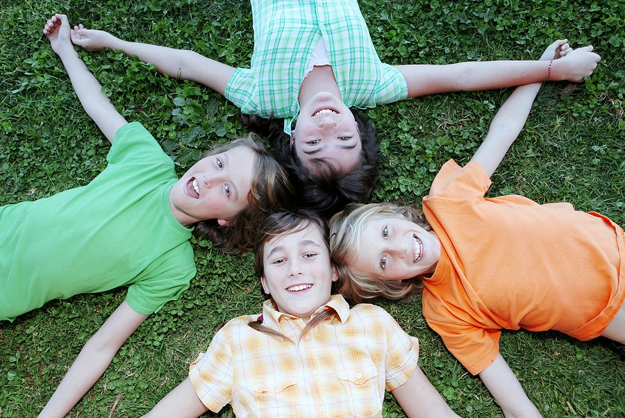 Aerial photo of a group of four, happy, smiling kids at summer camp with their heads together.
